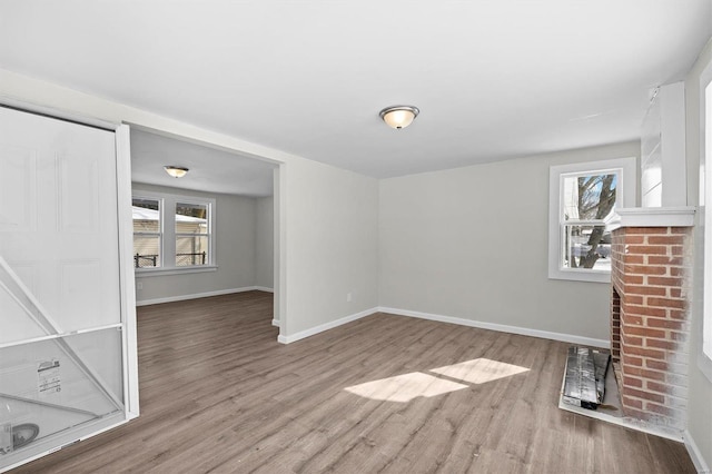 unfurnished living room with a healthy amount of sunlight, baseboards, and wood finished floors