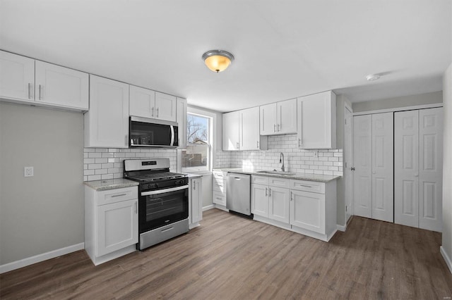 kitchen featuring stainless steel appliances, white cabinetry, a sink, and wood finished floors