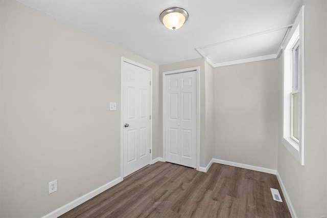 unfurnished bedroom featuring a closet, multiple windows, baseboards, and wood finished floors