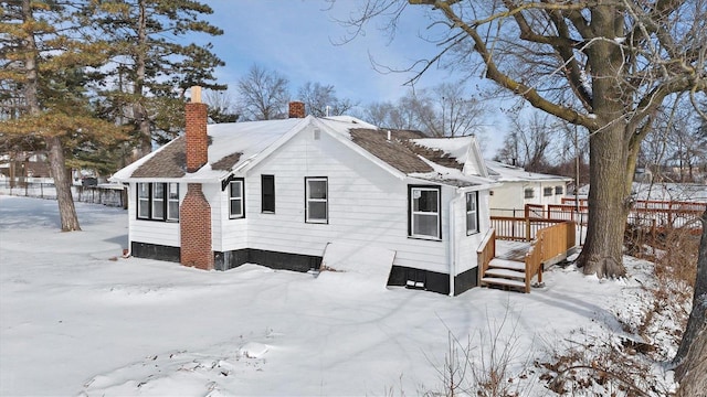 snow covered property featuring a chimney and a wooden deck