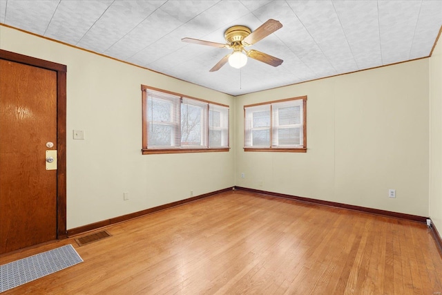 empty room featuring a ceiling fan, light wood-type flooring, visible vents, and baseboards