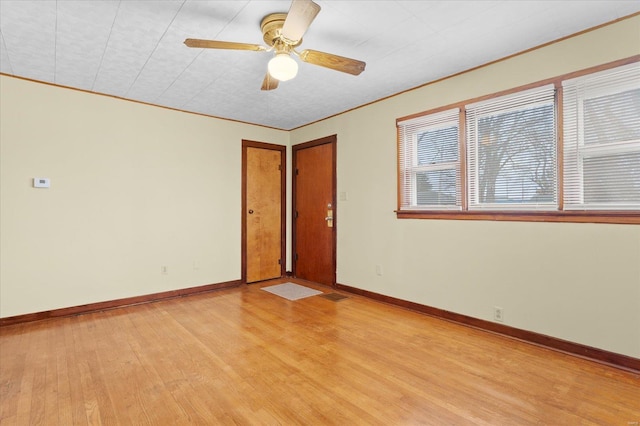 unfurnished room with crown molding, baseboards, and light wood-style floors