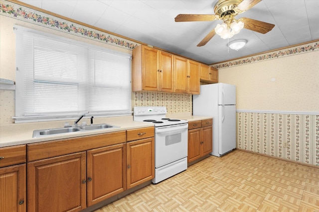 kitchen with wallpapered walls, white appliances, a sink, and light countertops