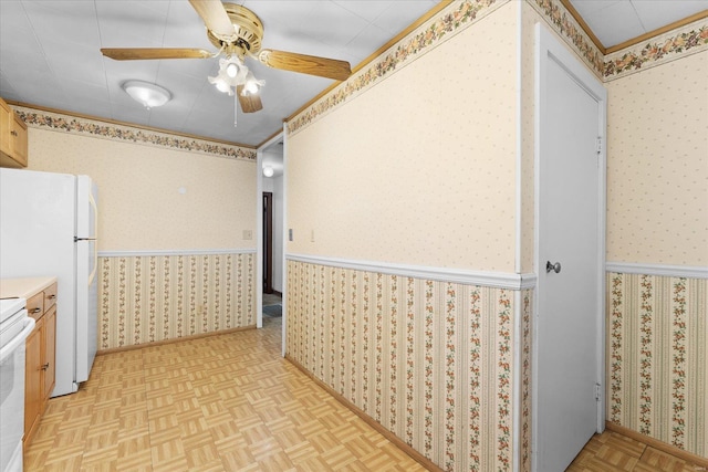 kitchen featuring wallpapered walls, wainscoting, ceiling fan, freestanding refrigerator, and light countertops