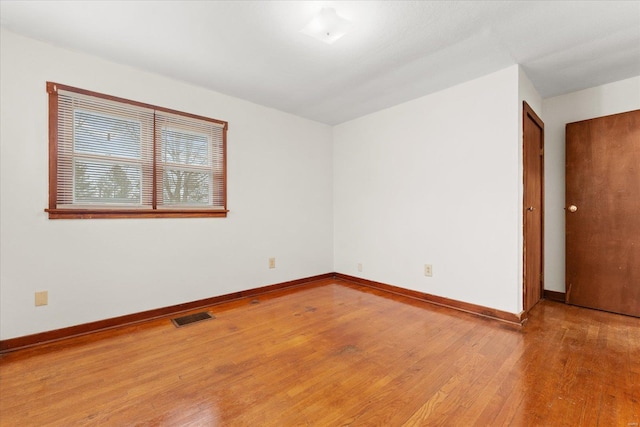 spare room featuring baseboards, visible vents, and hardwood / wood-style floors