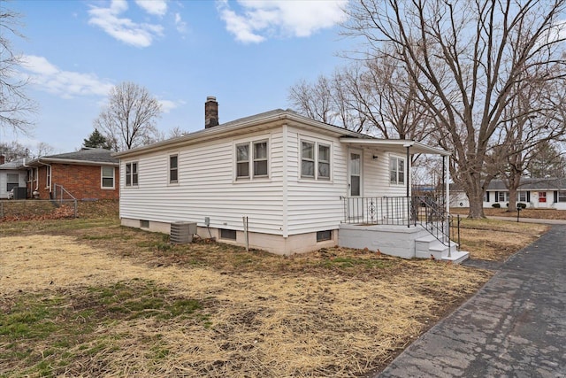 bungalow-style house with a chimney and central AC