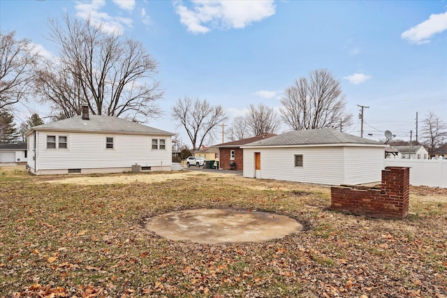 back of house featuring a yard, a chimney, and fence