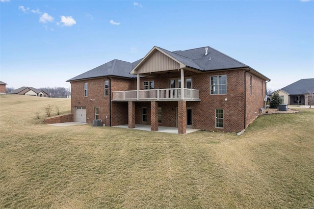 back of property with a patio, an attached garage, a yard, central air condition unit, and brick siding