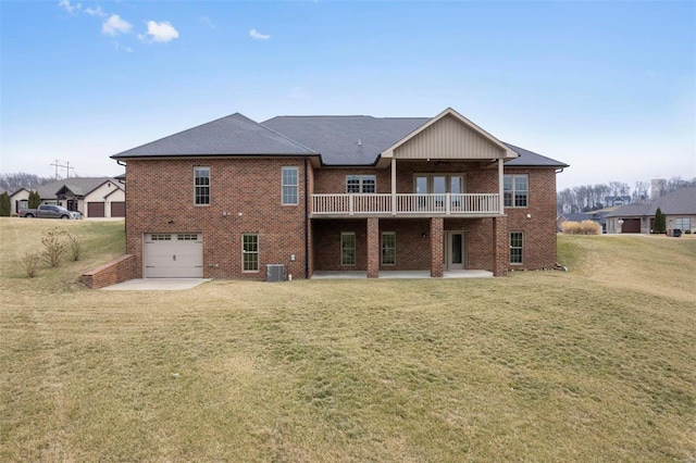 back of house featuring a garage, brick siding, a lawn, and a patio area