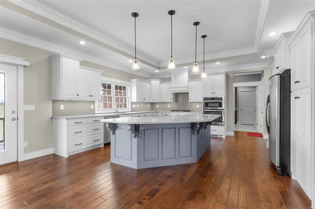 kitchen with white cabinetry, appliances with stainless steel finishes, a raised ceiling, and light countertops