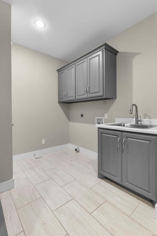 washroom featuring cabinet space, baseboards, hookup for a washing machine, hookup for an electric dryer, and a sink