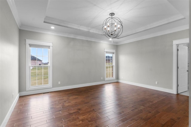 spare room with dark wood-style floors, plenty of natural light, a tray ceiling, and an inviting chandelier