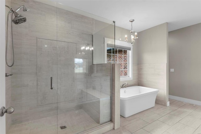 full bathroom with a freestanding bath, a stall shower, tile walls, and an inviting chandelier