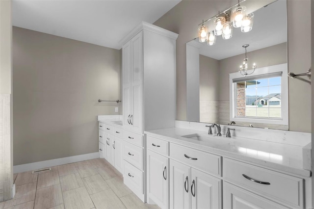 full bath featuring baseboards, vanity, and a notable chandelier