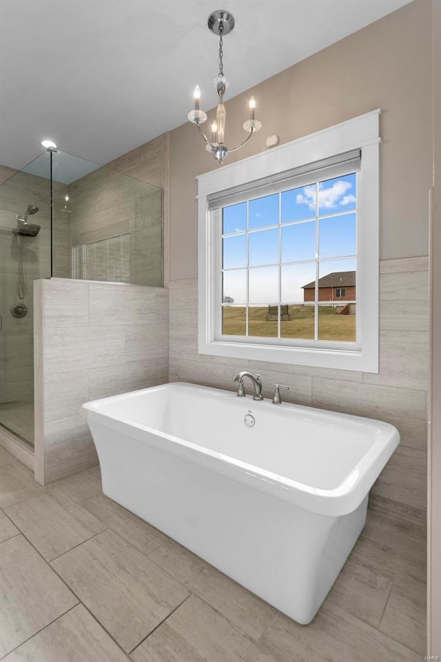 bathroom with a freestanding tub, a notable chandelier, tile walls, and tiled shower