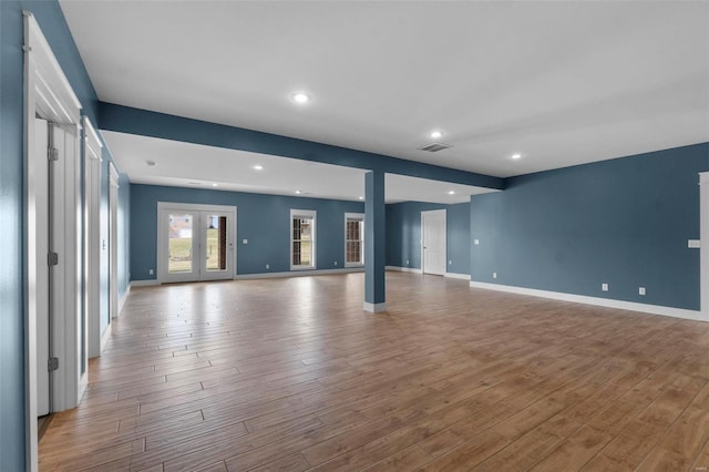 unfurnished living room featuring french doors, wood finished floors, visible vents, and baseboards