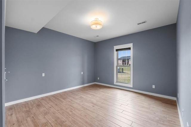 unfurnished room featuring wood finished floors, visible vents, and baseboards