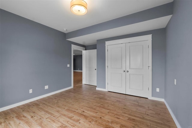 unfurnished bedroom featuring light wood-type flooring, baseboards, and a closet