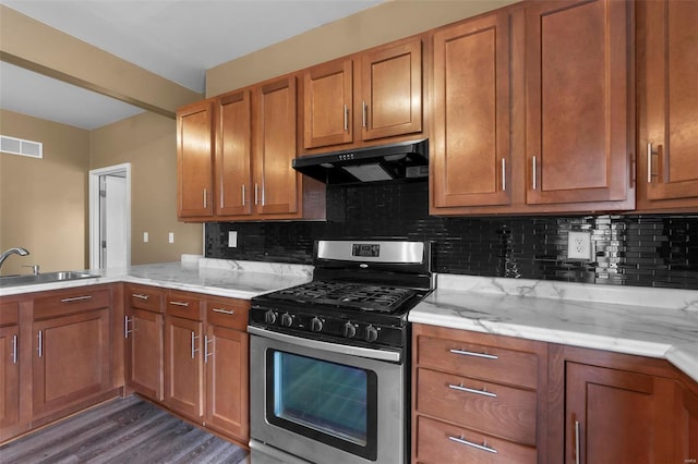 kitchen with brown cabinets, stainless steel range with gas cooktop, visible vents, and under cabinet range hood