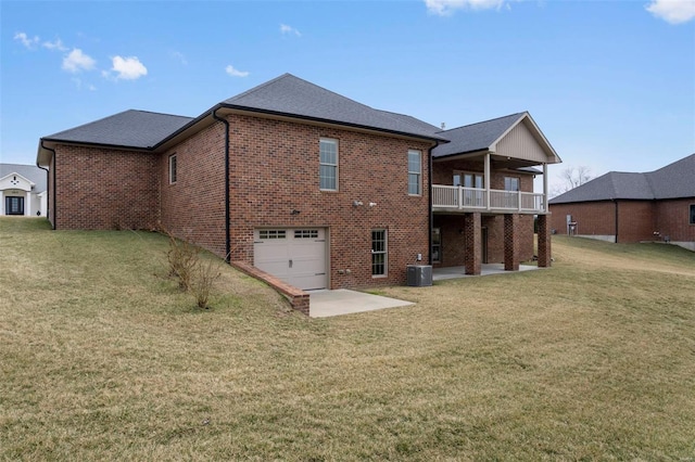 rear view of house with a lawn, a patio, an attached garage, central AC, and brick siding