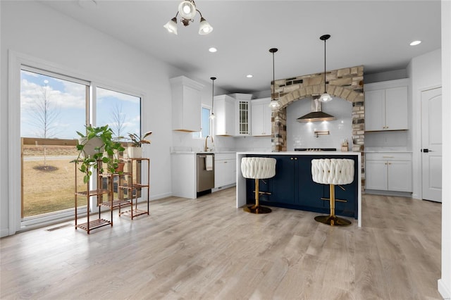 kitchen with light wood-type flooring, tasteful backsplash, a kitchen island, white cabinetry, and light countertops