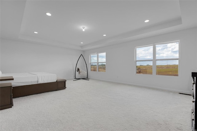 bedroom featuring a tray ceiling, recessed lighting, light colored carpet, and baseboards