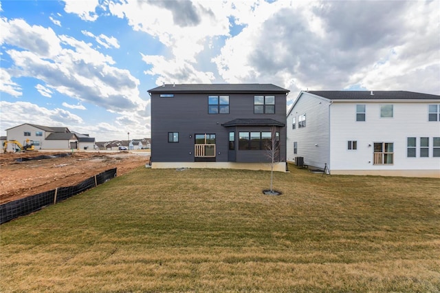 rear view of house with central air condition unit, a yard, and fence