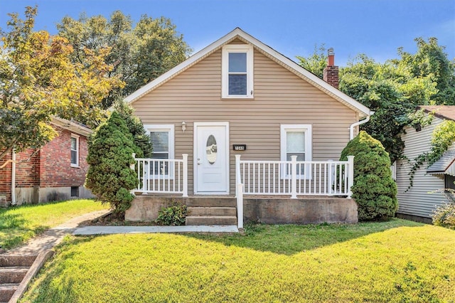 bungalow-style home with a porch, a chimney, and a front yard