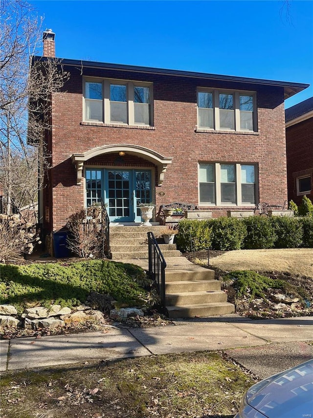 view of front facade featuring brick siding and a chimney