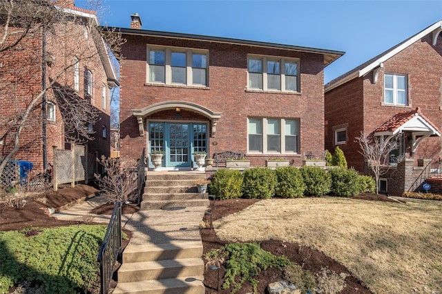 view of front of home featuring brick siding and a chimney