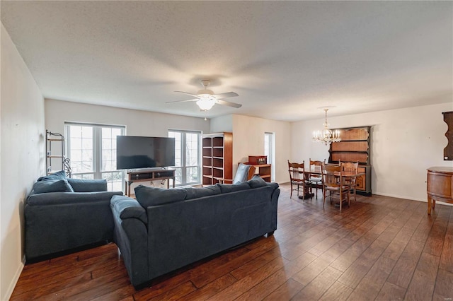 living room featuring baseboards, dark wood finished floors, a textured ceiling, and ceiling fan with notable chandelier