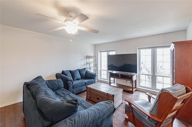 living area featuring ceiling fan, baseboards, and dark wood-type flooring