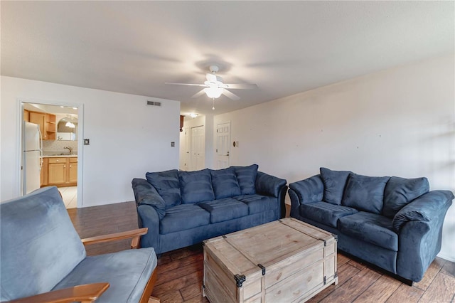 living room featuring ceiling fan, visible vents, and wood finished floors