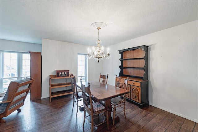 dining space featuring dark wood-style floors, a textured ceiling, baseboards, and an inviting chandelier