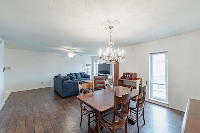 dining room with ceiling fan with notable chandelier, dark wood-style flooring, a textured ceiling, and baseboards