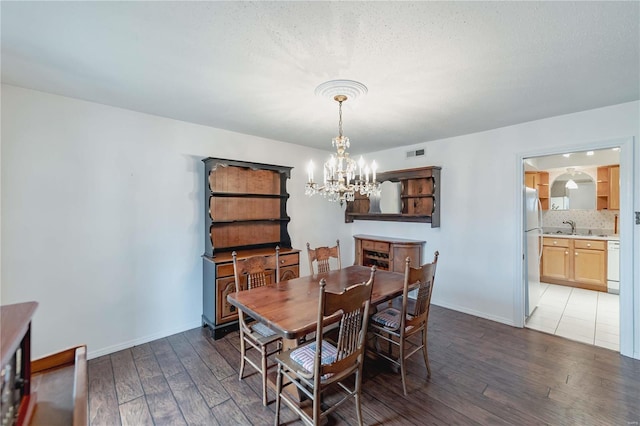 dining area featuring a chandelier, visible vents, baseboards, and hardwood / wood-style flooring