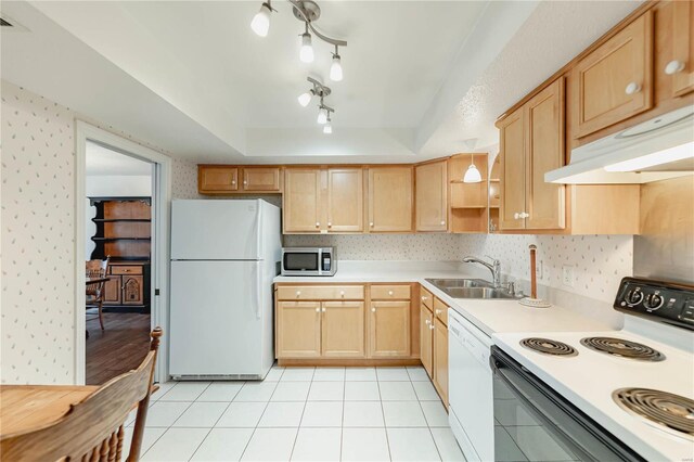 kitchen featuring under cabinet range hood, white appliances, a sink, a tray ceiling, and wallpapered walls