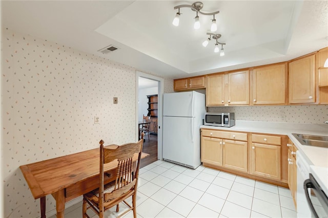 kitchen featuring wallpapered walls, stainless steel microwave, a tray ceiling, and freestanding refrigerator