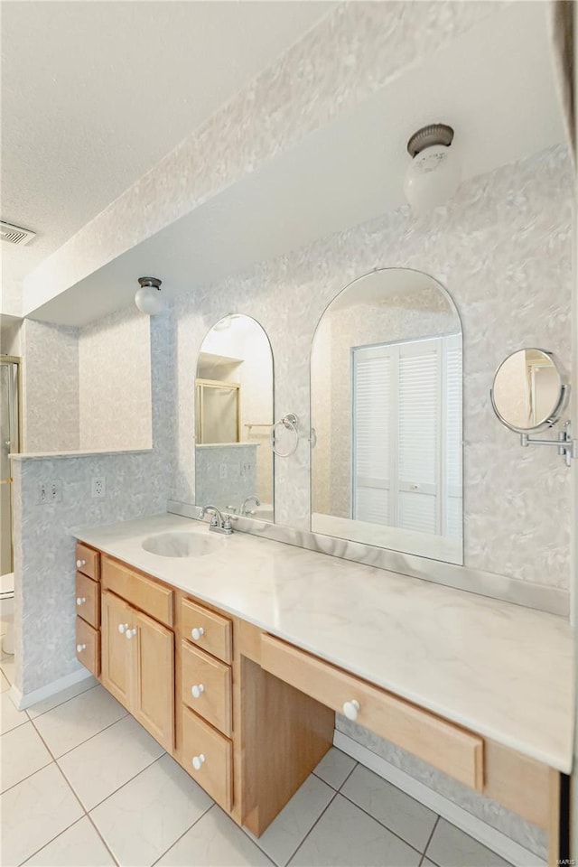 bathroom with a textured ceiling, tile patterned flooring, visible vents, vanity, and a shower with door