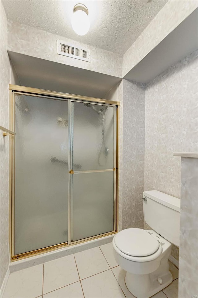 bathroom with toilet, a shower stall, visible vents, and a textured ceiling