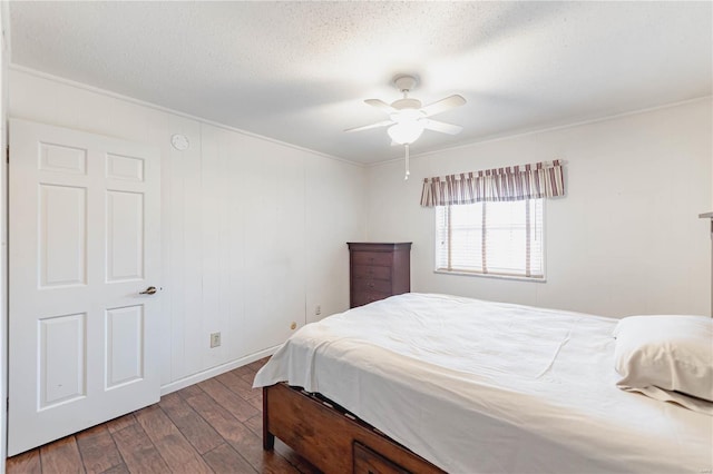 bedroom with a textured ceiling, ceiling fan, and dark wood-type flooring