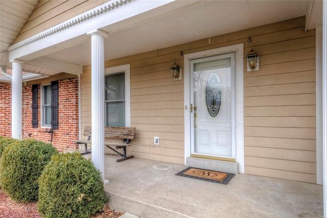 entrance to property featuring brick siding and covered porch