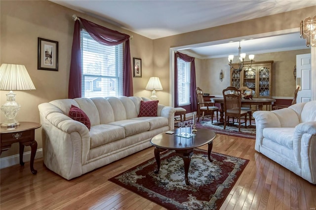 living room featuring hardwood / wood-style floors, crown molding, a notable chandelier, and baseboards