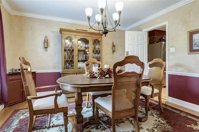 dining space featuring a notable chandelier, crown molding, light wood-type flooring, and baseboards