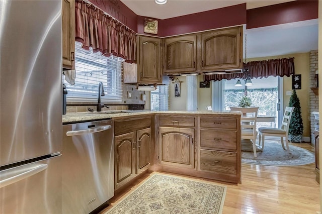 kitchen with light wood finished floors, a healthy amount of sunlight, stainless steel appliances, and a sink