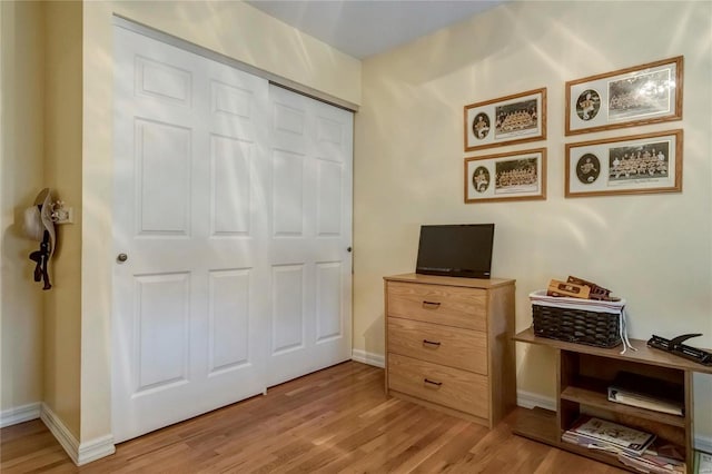 interior space with baseboards, light wood-type flooring, and a closet