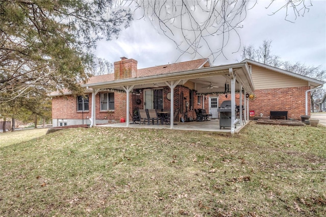 rear view of house with a yard, brick siding, a chimney, and a patio area