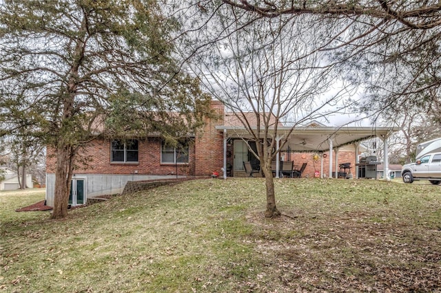 back of property featuring brick siding, a lawn, and a chimney