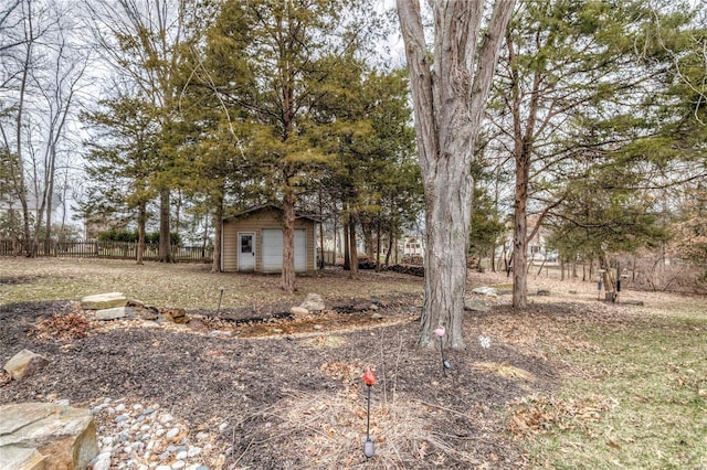 view of yard featuring a detached garage, an outbuilding, a shed, and fence