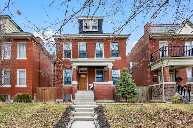 view of front of home with brick siding, fence, and a balcony